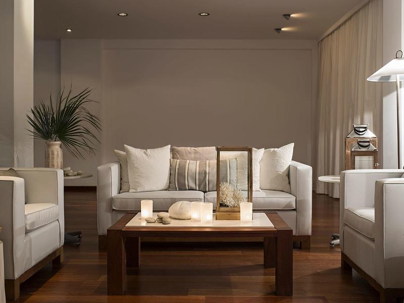 Moderner Hotel-Loungeraum mit weißen Sesseln, Sofa und Holztisch auf Holzboden.