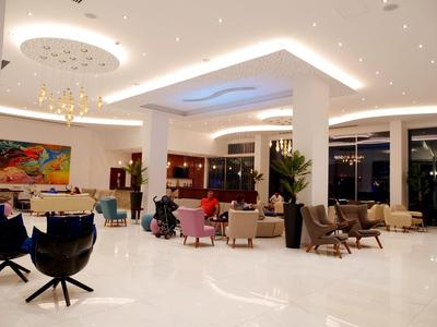 Elegante hotellobby met witte vloeren, moderne zithoeken en stijlvolle verlichting.
