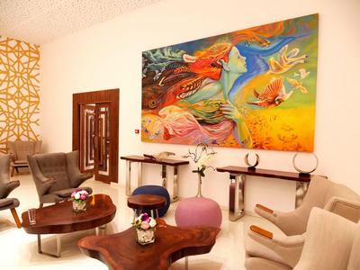 Modern ingerichte woonkamer met kleurrijk schilderij, fauteuils en decoratieve elementen.