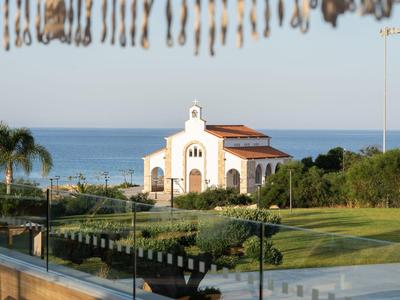 Kirche nahe Küste mit Garten und Meer im Hintergrund bei klarem Himmel.