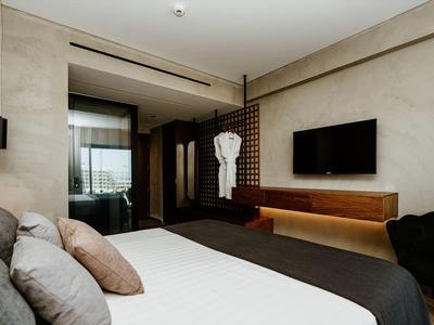 Modernes Hotelzimmer mit großem Bett, Wandfernseher und stilvoller Beleuchtung.