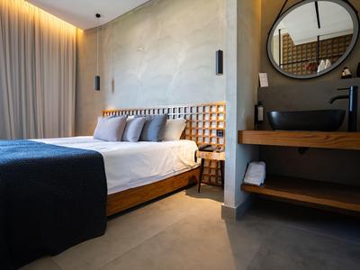 Modernes Hotelzimmer mit großem Doppelbett, gemütlicher Beleuchtung und elegantem Waschtisch.