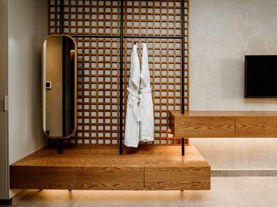 Elegantes Hotelzimmer mit Holzelementen, Bademänteln und modernem Fernseher an der Wand.