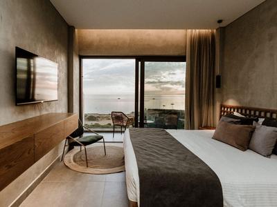 Modernes Hotelzimmer mit Meerblick, großem Bett, Wand-TV und minimalistischem Design.
