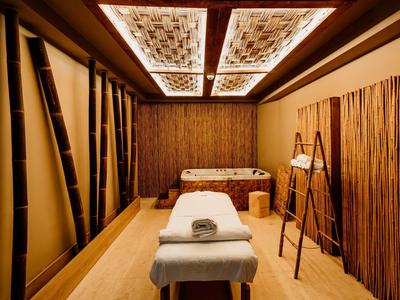 Warmer Spa-Raum mit Massagetisch, Bambusdekoration und sanfter Beleuchtung.