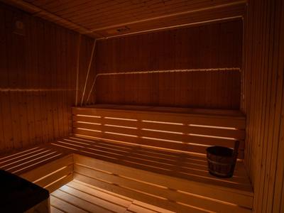 Holzsauna mit mehrstufigen Sitzbänken, einem Eimer und gedämpftem Licht.