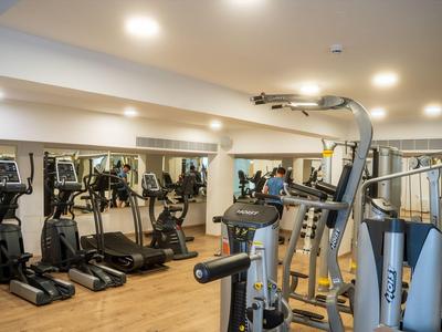Moderne Fitnessgeräte in einem hellen, gut ausgestatteten Hotel-Fitnessraum mit Holzfußboden.