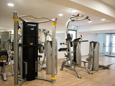Modernes Fitnessstudio mit vielseitigen Trainingsgeräten und hellem Holzfußboden.