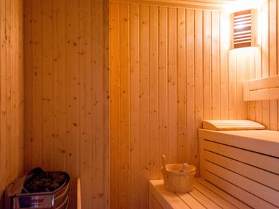 Warme Holzsauna mit Ruheliegen, Eimer und Aufgussgerät für entspannten Urlaub.