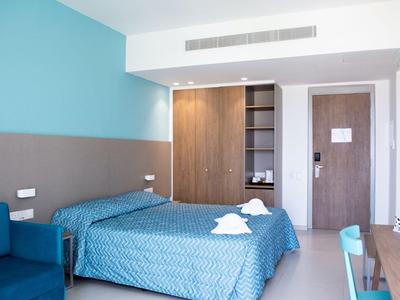 Modernes Hotelzimmer mit Doppelbett, blauer Wand und Holzschrank.