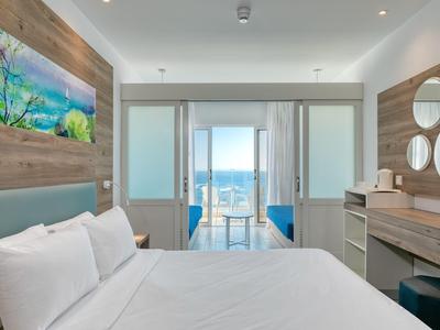 Modernes Hotelzimmer mit Doppelbett, Schreibtisch, Kunst an der Wand und Meerblick durch große Fenster.