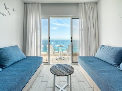 Stanza luminosa arredata con divani blu e vista mare attraverso grandi finestre di vetro