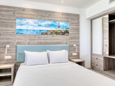 Camera moderna con letto bianco, pannelli in legno e quadro marino sulla parete.