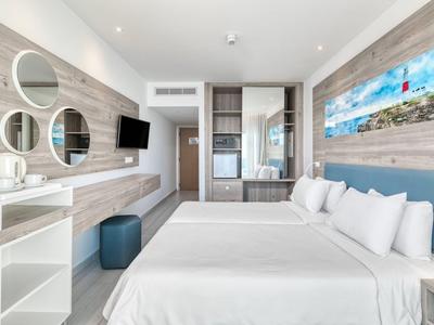 Camera d'hotel luminosa con due letti, TV a schermo piatto e arredamento moderno.