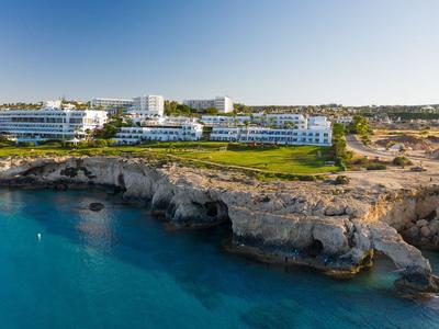 Resort hotel sulla costa rocciosa con vista sul mare azzurro sotto un cielo sereno.