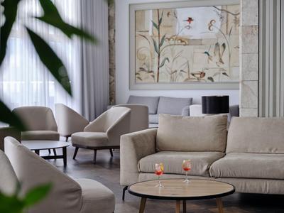 Accogliente area lounge con poltrone comode, divano e grande opera d'arte murale in un hotel.