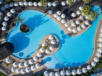 Vista aerea di una grande piscina dell'hotel circondata da lettini e ombrelloni.