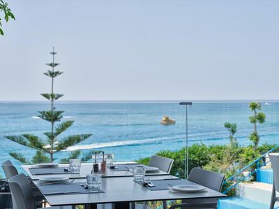 Moderner Außenbereich eines Hotels mit Meerblick, Tisch und Stühlen auf einer Terrasse.