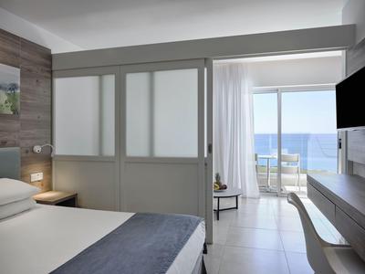 Modernes Hotelzimmer mit Meerblick, Schiebetüren und Balkon mit Sitzgelegenheit.