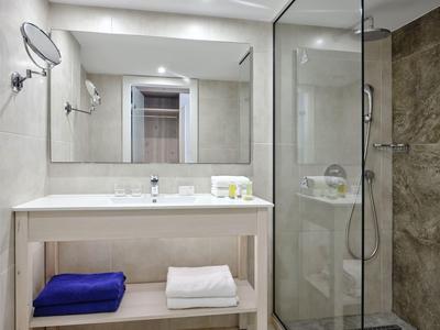 Modernes Hotelbad mit großem Spiegel, weißen Handtüchern und Glasdusche.