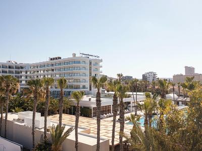 Moderne weiße Gebäude und Palmen unter klarem blauem Himmel in einer sonnigen Stadt.