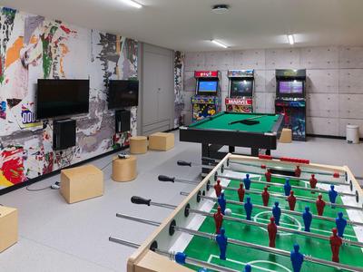 Freizeitraum mit Kicker, Billardtisch, Arcade-Spielen und bunter Wandgestaltung.