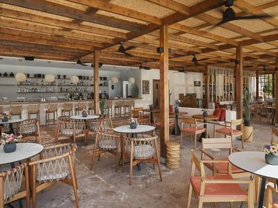 Una zona de comedor rústica abierta con muebles de madera y techo cubierto de madera.