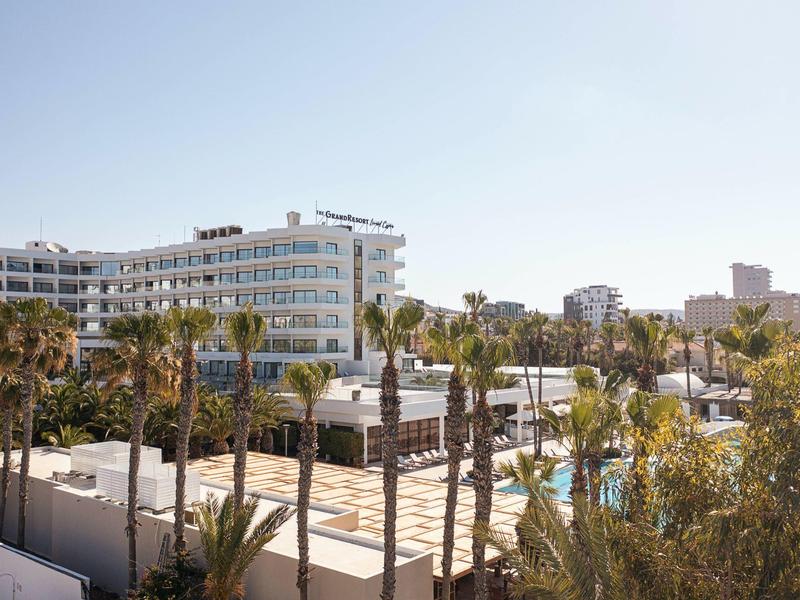 Moderne weiße Gebäude und Palmen unter klarem blauem Himmel in einer sonnigen Stadt.