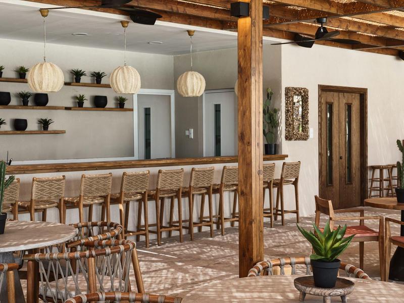 Moderner Innenraum mit Holzstühlen, langen Theken, weißen Wänden und hängenden Lampen.