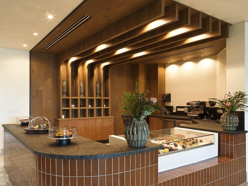 Moderne Küche mit braunen Fliesen, Holzdecke und großer Arbeitsfläche mit Dekoration.