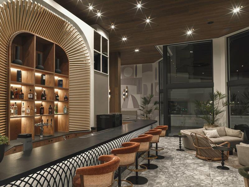 Modernes Café mit dunklem Holzdekor, runden Holzhockern, Regalwand und großen Panoramafenstern.