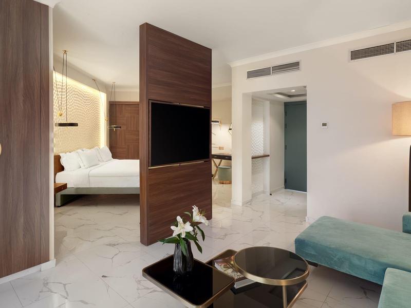 Moderne Hotel-Suite mit Marmorfußboden, gemütlichem Sofa und Schlafzimmer im Hintergrund.