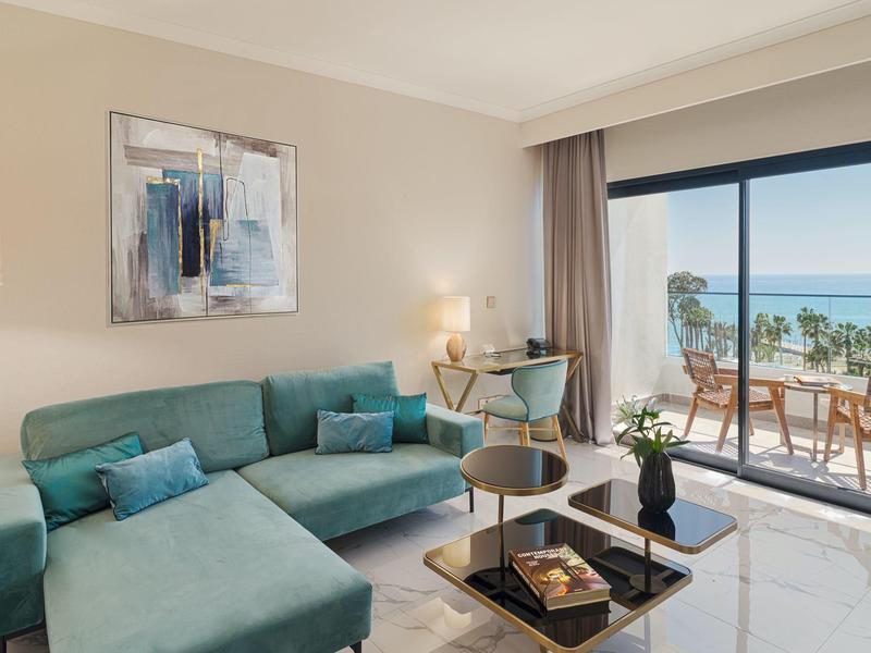 Modern eingerichtetes Wohnzimmer mit Sofa und Blick auf Terrasse und Meer.