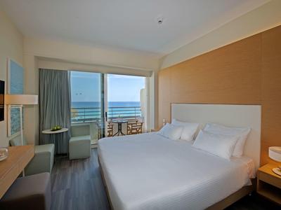 Nowoczesny pokój hotelowy z dużym łóżkiem i balkonem z widokiem na morze.