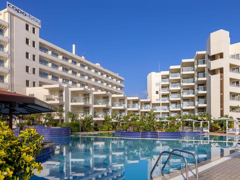 Großes modernes Hotel mit mehreren Etagen, Balkonreihen, Pool und klar blauem Himmel.