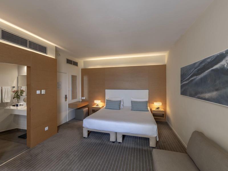 Modernes Hotelzimmer mit großem Bett, warmem Licht, Schreibtisch und offenem Badezimmer.