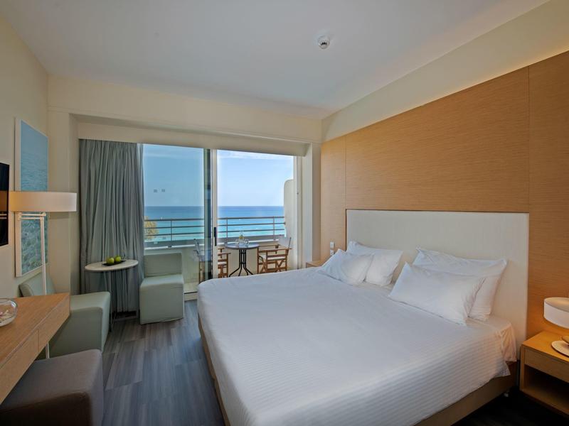 Nowoczesny pokój hotelowy z dużym łóżkiem i balkonem z widokiem na morze.