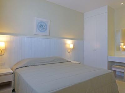 Een eenvoudig ingericht slaapkamer met tweepersoonsbed, nachtkastjes en wandlampen.