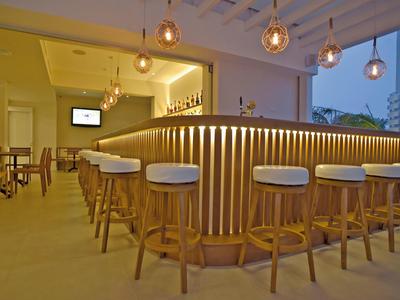 Moderne hotelbar met een gebogen bar en verschillende krukken onder hanglampen.