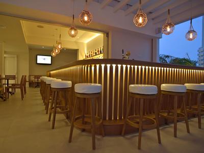 Moderní hotelový bar s kulatými barovými stoličkami a teplým závěsným osvětlením