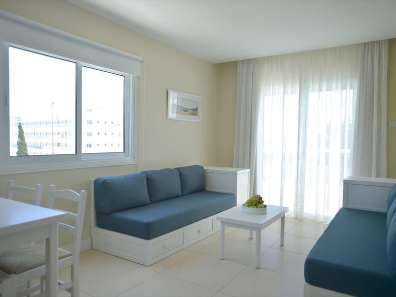 Lichte woonkamer met twee blauwe sofa's, kleine witte tafel en grote ramen.