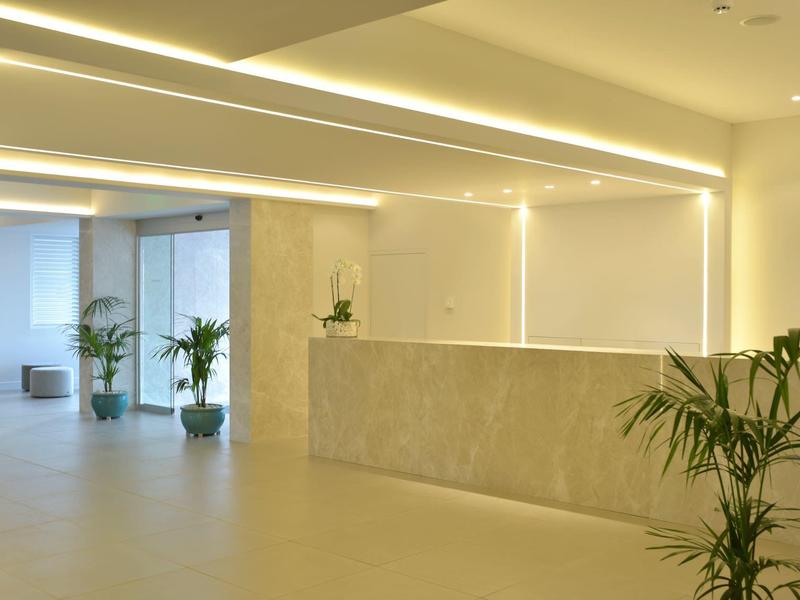 Moderne en lichte hotelreceptie met planten en minimalistisch ontwerp.