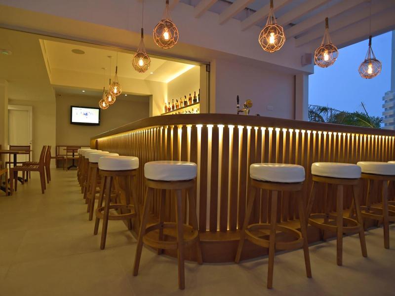 Moderne hotelbar met verlichte toonbank en barkrukken in een warme sfeer.