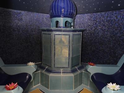 Ein runder Raum mit blauem Kuppeldach, Kacheln und Sitzen, Sternenhimmel an der Decke.