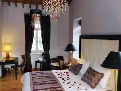 Elegantes Schlafzimmer mit Holzbalkendecke, Kronleuchter, Doppelbett und dunklen Möbeln.