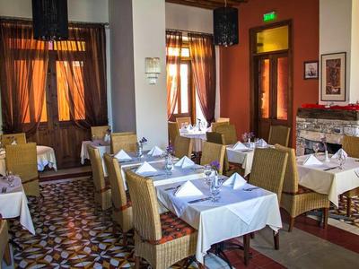 Restaurant mit gedeckten Tischen, weißen Tuchdecken, beige Stühlen und warmem Tageslicht durch Fenster.