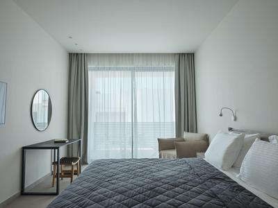 Nowoczesny pokój hotelowy z łóżkiem podwójnym, miejscem do siedzenia i dużym oknem z zasłonami.