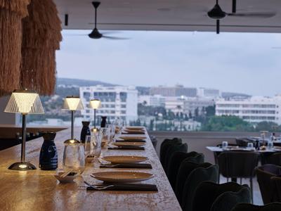 Elegancka restauracja z nakrytym stołem i widokiem na miasto i góry w świetle dziennym.