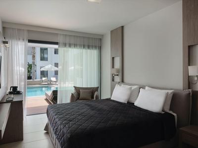 Nowoczesny pokój hotelowy z łóżkiem podwójnym i dostępem do tarasu i basenu.