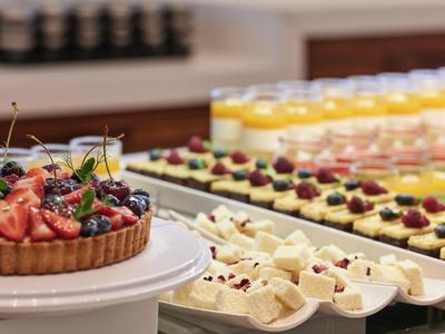 Ein Tisch mit verschiedenen Desserts, darunter ein Obstkuchen und kleine Kuchenstücke mit Beeren.